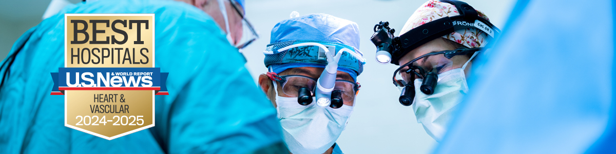 Surgeons wearing masks and loupes, looking down in focused concentration, and Best Hospitals badge showing national ranking for Cardiology & Heart Surgery, 2024-25